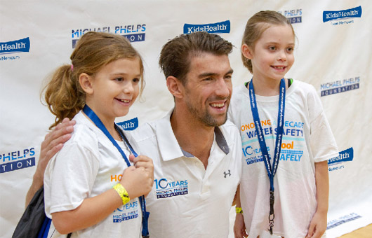 Michael Phelps poses for a photo with two happy girls who have just completed an I'm Healthy challenge.