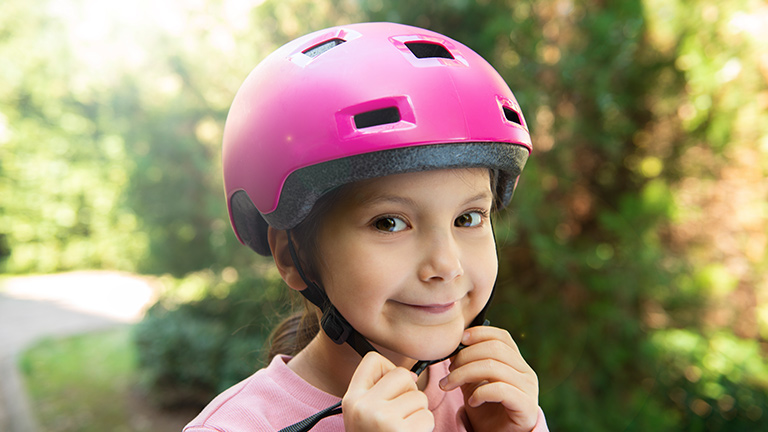 A girl buckles her bike helmet
